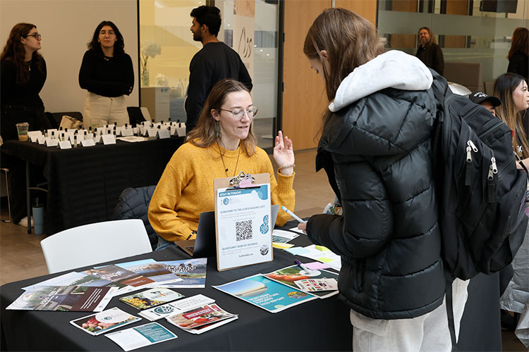  a woman in a sweater speakers with students at a table